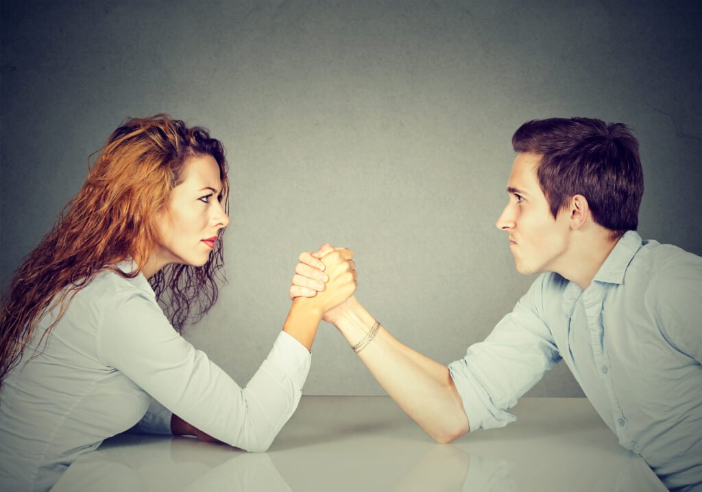 A woman and a man arm wrestling metaphorically for control within their relationship.